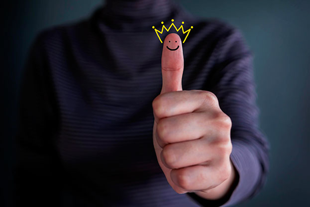 A hand showing thumbs up with a happy face and golden crown