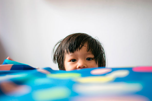 a kid looking over a table to see better what's on the table itself