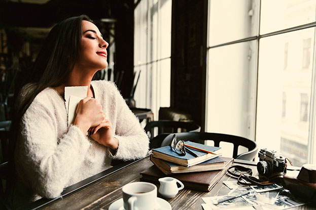 woman holding two pieces of paper to her hearth after reading an emotional text on them